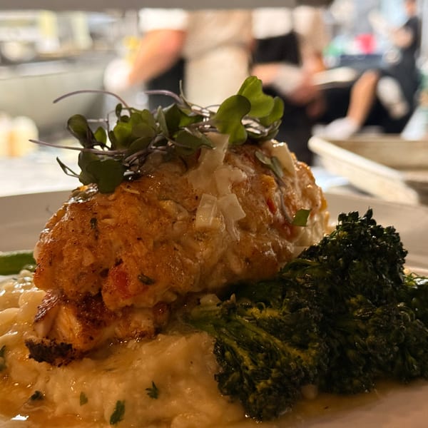 Close-up of a Live Fire Chefs Italian-American dish with broccolini, mashed potatoes, and a crab cake.