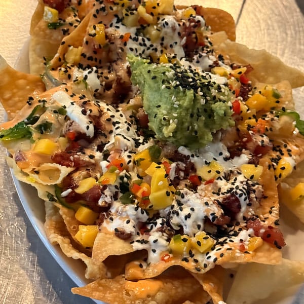 Crispy wonton nachos topped with tuna, mango salsa, guacamole, and sesame seeds.